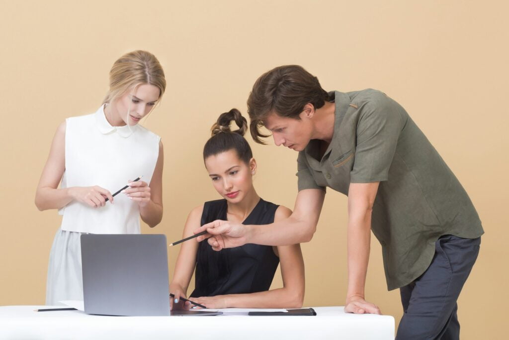 Grupa ludzi pracująca przy laptopie nad projektem.